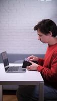 A man sitting at a table with a laptop and a credit card video