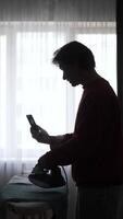 A man ironing on a phone video