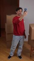 A man taking a selfie with his cell phone in a room with boxes video
