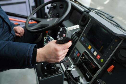 Close-up view of a driver operating heavy machinery with precision controls while on duty in an urban setting during daylight hours. photo