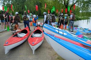 Kayak enthusiasts gather by the waterway with colorful kayaks and paddles preparing for an outdoor adventure in the afternoon light. photo