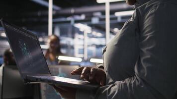 Close up of data center engineer using laptop to monitor neural network AI LLM visualization. Worker using notebook to oversee servers powering machine learning processes, camera A video