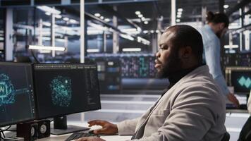 Satisfied data center employee finishing system maintenance on supercomputers. Smiling technician pleased by successful AI model training results on PC while overseeing server infrastructure, camera A video
