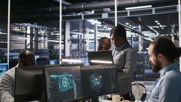 Portrait of happy technician next to data center colleagues review AI diagnostics. Cheerful IT specialist and coworkers analyze neural network performance to maintain operational reliability, camera A video