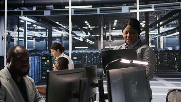 Data center system administrator pleased by neural network outputs after completing software updates. IT expert smiling, looking at laptop screen, optimizing configuration server hub rigs, camera A video
