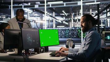 Engineer using green screen mockup PC in data center to update servers tech, configuring equipment using software tools. Server room worker reviewing hardware analytics on chroma key PC, camera A video