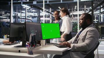 Data center admin inspecting gear using green screen mockup PC, doing maintenance tasks. African american server farm worker using chroma key computer, conducting system checks, camera A video