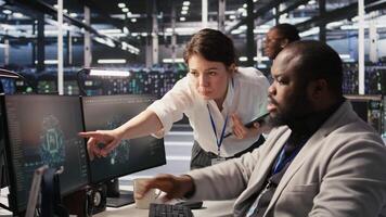 Lead data center admin overseeing IT expert integrating AI in equipment rigs. African american employee under server farm team leader supervision using deep learning for operational tasks, camera A video