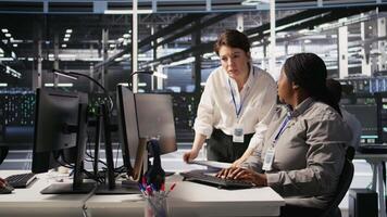Data center team leader and IT expert reviewing performance dashboards of AI equipment rigs. Server room manager oversee system administrator examining machine learning algorithms on screen, camera A video