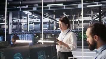 Data center team leader supervising system operations supporting neural networks and analytics workflows. Server hub manager monitoring engineering team managing AI training datasets, camera A video