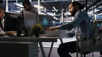 Upset data center worker packing personal items at workstation after being replaced by AI. Programmer removing belongings from server hub workplace desk, fired by artificial intelligence, camera A video