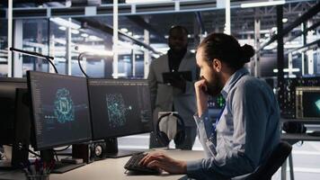 System administration team collaborating on AI automation deployment in data center. Server farm staff members adjusting machine learning configurations, working together, camera A video