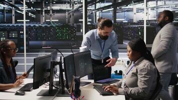 Server room manager providing feedback to employee managing AI training datasets. Team leader talking with technician in data center supervising system operations supporting neural networks, camera A video
