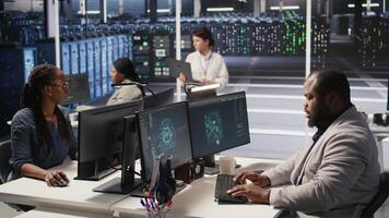 Stressed technician in data center managing AI server infrastructure, drinking coffee. African american worker using PC to run artificial intelligence, panicked by deadline, camera A video