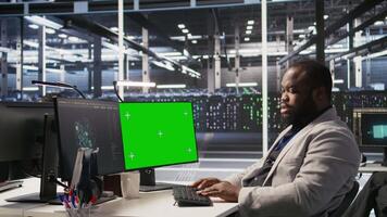 Data center programmer coding on green screen PC, monitoring AI systems. Server hub IT expert uses mockup computer to oversee rackmounts powering deep learning processes, camera A video