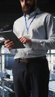 Vertical Portrait of smiling engineer in data center monitoring neural network LLM visualization. Cheerful server hub IT specialists overseeing rigs powering machine learning processes, camera A video