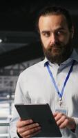 Vertical Portrait of smiling engineer in data center monitoring neural network LLM visualization. Cheerful server hub IT specialists overseeing rigs powering machine learning processes, camera B video
