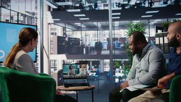 Multiethnic business leaders engaged in a web conference in office lobby, exchanging strategy and negotiation points with remote partners in a global multicultural work environment. Camera A. video