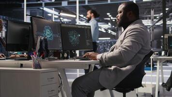 Exhausted server farm employee stretching back after sitting too long at computer desk. Fatigued man in data center office relaxing muscles, stressed by long hardware troubleshooting session, camera A video