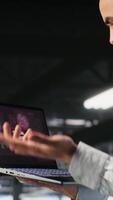 Vertical Annoyed engineer in data center reacting to critical error message on laptop. Irked IT professional attempts to resolve system fault impacting backend infrastructure performance, camera B video