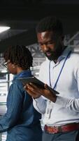 Vertical Engineer walking on data center industrial platform, performing system maintenance. IT professional using tablet to do upgrades, resolving bugs and enhancing infrastructure stability, camera B video