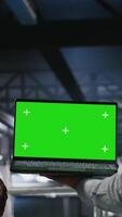 Vertical Army tech specialist in data center and coworkers using green screen laptop to troubleshoot military computer systems. Soldier and command center server room admins using chroma key notebook, camera B video