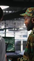 Vertical Army operators in data center using laptop to run drone control software, looking at mission map overlay. Military experts doing strategic deployment of autonomous aerial vehicles, camera B video