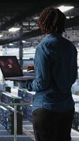 Vertical Data center software developer panicking after receiving critical error popup on laptop display. African american woman in server hub alerted by bugs causing low hardware performance, camera A video