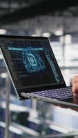 Vertical Close up of IT specialist in server room doing AI deep learning automatization. Data center software developer using notebook, doing hardware maintenance using AI, camera B video