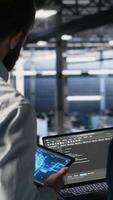 Vertical Server farm manager overseeing workers doing infrastructure AI machine learning automatization. Data center team leader supervising employees using artificial intelligence, camera B video