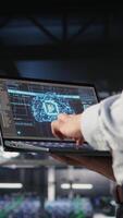 Vertical Close up of IT specialist in server room doing AI deep learning automatization. Data center software developer using notebook, doing hardware maintenance using AI, camera A video