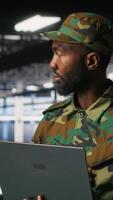 Vertical Army IT specialist in data center using laptop to defend networks against cyber threats. Military command center admin using notebook to identify potential intrusions or malicious activities, camera B video