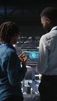 Vertical Data center engineering team doing maintenance on rigs handling AI processing tasks. Server hub teamworking colleagues managing storage arrays supporting deep learning training workflows, camera A video