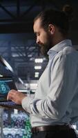 Vertical Server farm IT expert managing storage arrays supporting machine learning training workflows. Technician on industrial platform doing maintenance on rigs handling AI processing tasks, camera A video