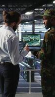 Vertical Military experts in data center reviewing drone surveillance feed on laptop screen. Army units in high tech server room doing battlefield reconnaissance operations using notebook, camera A video