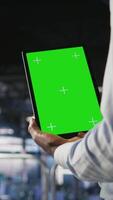 Vertical Data center worker using green screen mockup tablet, doing maintenance on rigs handling AI tasks. Server hub admin using chroma key device to manage storage arrays supporting deep learning, camera A video