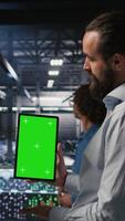 Vertical Military personnel overseeing AI computing operations on isolated screen tablet in high tech server facility. Army tech experts using chroma key device to oversee communication systems, camera A video