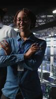 Vertical Portrait of smiling data center admin next to coworkers running diagnostics on equipment to identify errors. Happy woman next to IT experts working to prevent failure and minimize downtime, camera A video