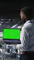 Vertical Data center programmers on industrial platform using green screen laptop, collaborating on tasks. Server hub workers visualizing large language model architecture using mockup notebook and PC video
