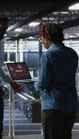 Vertical Worried workers trying to fix hacked infrastructure systems. Panicked engineers in data center react to ransomware warning on laptop screen, scrambling to launch emergency response protocol, camera A video
