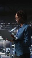 Vertical Portrait of joyful computer scientist in data center monitoring neural network LLM visualization. Upbeat woman in server farm overseeing rigs powering machine learning processes, camera A video