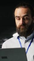 Vertical Data center admins monitoring artificial intelligence LLM visualization. Teamworking server room employees cooperating, overseeing rigs powering deep learning processes, camera B video