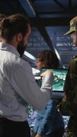 Vertical Army operators in data center using laptop to run drone control software, looking at mission map overlay. Military experts doing strategic deployment of autonomous aerial vehicles, camera A video
