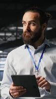 Vertical Technicians on data center platform using devices to monitor neural network LLM visualization. Industrial server hub engineering team overseeing rigs powering machine learning processes, camera B video