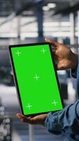 Vertical Data center engineers monitoring neural network LLM visualization using green screen tablet. Server farm IT experts oversee rigs powering machine learning processes using chroma key device, camera B video