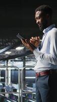 Vertical Software developers on data center industrial platform analyzing performance outputs on devices. Server room IT specialists collaborating on finetuning mainframes configurations, camera A video