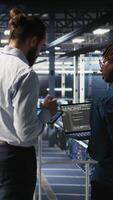 Vertical Data center engineering team doing maintenance on servers used for artificial intelligence processing. IT experts manage data center arrays used for machine learning training with tablet, camera A video