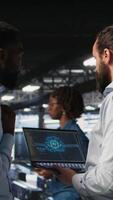 Vertical Server farm coworkers doing infrastructure AI machine learning automatization. Data center computer scientists collaborating to maintain servers using artificial intelligence, camera A video