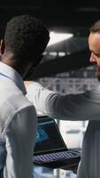 Vertical Data center workers cooperating, doing maintenance on rigs handling AI processing tasks. Server hub admins doing brainstorming, managing storage arrays supporting deep learning technology, camera B video