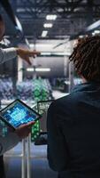 Vertical Server farm manager overseeing workers doing infrastructure AI machine learning automatization. Data center team leader supervising employees using artificial intelligence, camera A video